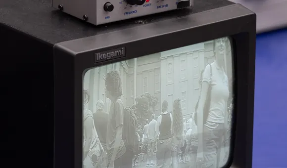 A small black and white tv monitor displays a fuzzy image on the screen. On top of it sits a box with nobs.
