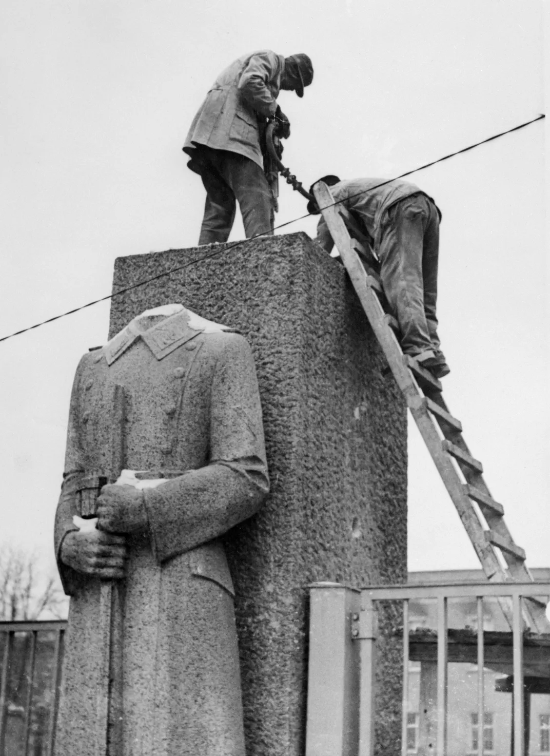 In 1945, workmen in Berlin climb atop a headless statue of a Nazi soldier near barracks now occupied by U.S. troops. The statue was later demolished as part of the de-Nazification program.
