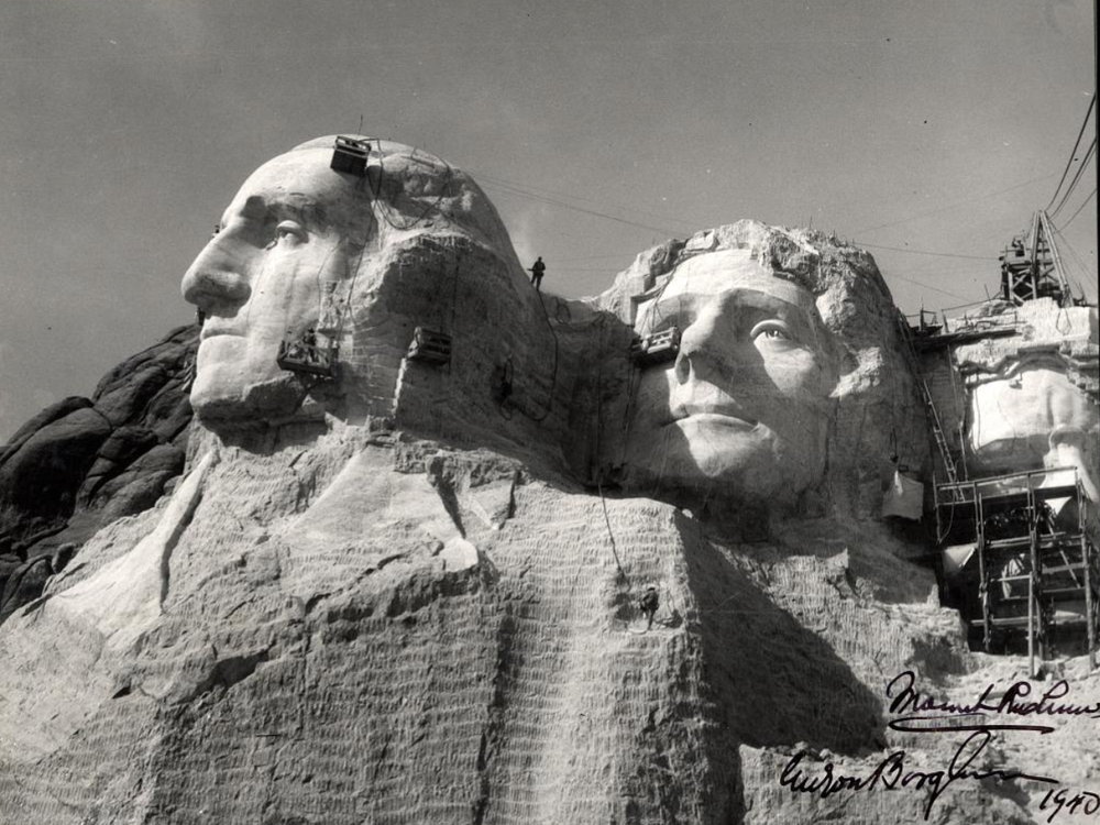 A close up view of workers carving the heads of George Washington and Thomas Jefferson on Mount Rushmore