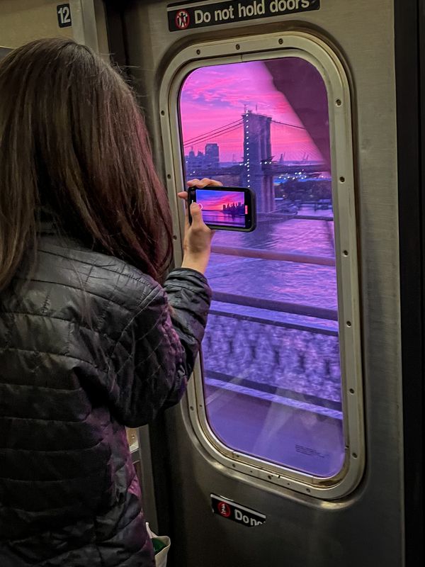 Sunset Over the Brooklyn Bridge Through a Subway Window and a Phone thumbnail