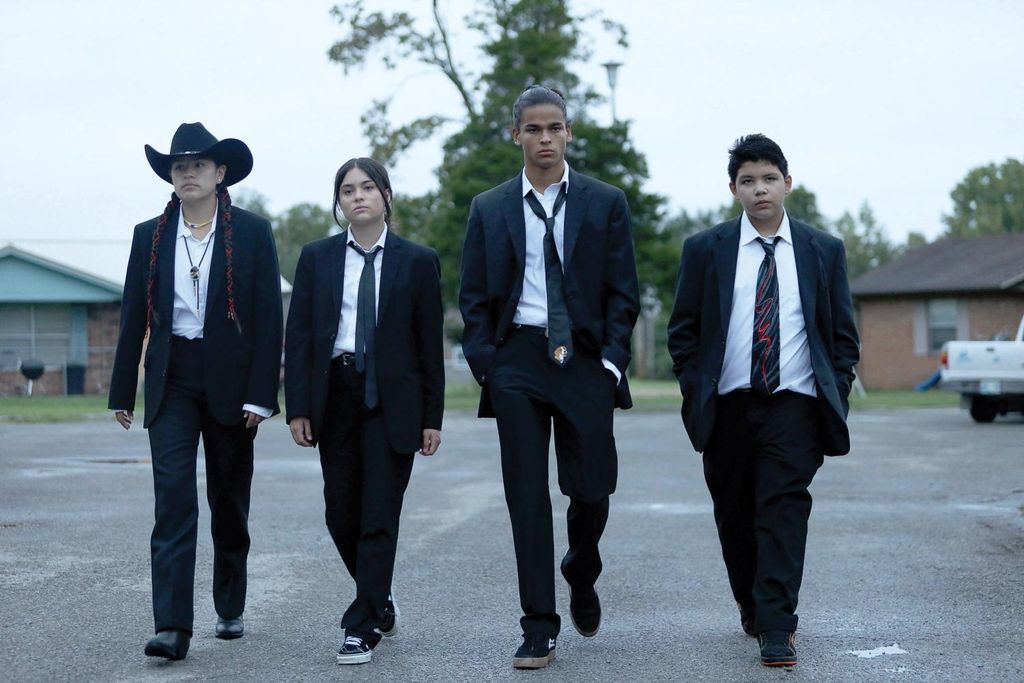 four Native American teenagers in black suits walking
