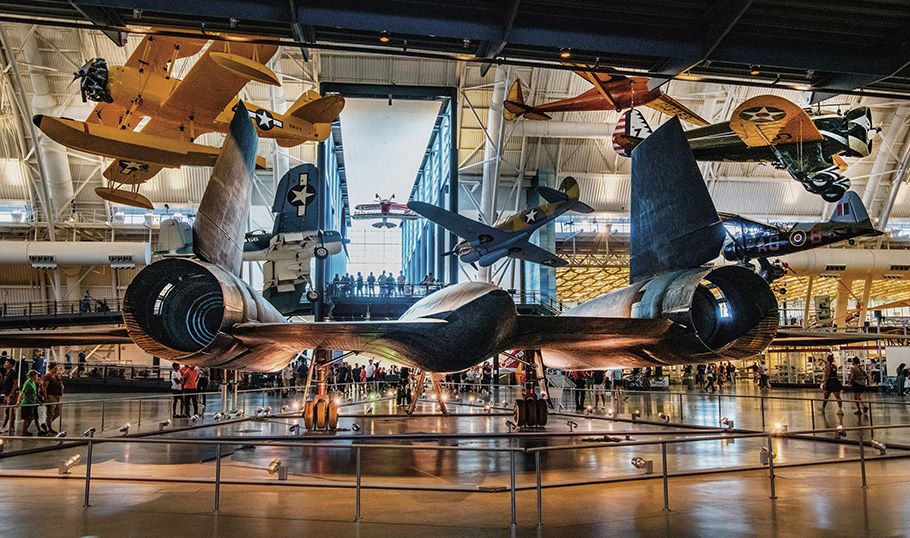 Multiple aircraft are on exhibit, including five suspended from the ceiling. Displayed on the floor is the Lockheed SR-71, viewed from the rear--the exhaust nozzles of the powerful jet engines in full view.