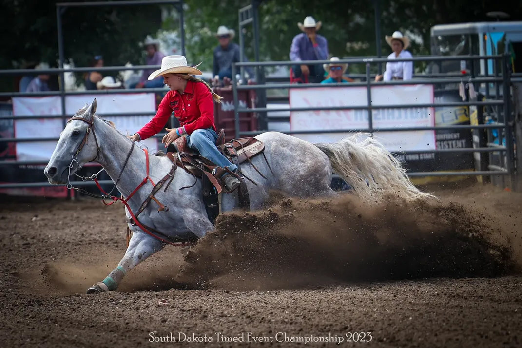 A horse kicks up a lot of dust as it puts on a show, with the help of a rider.