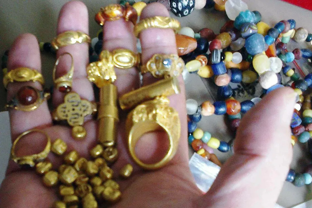 gold jewelry and beads held in a hand