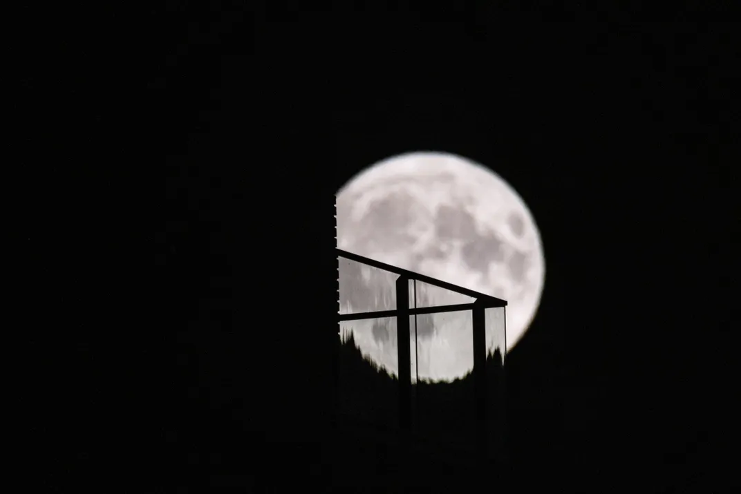 Strawberry full moon appears behind the balcony of a high building in Eindhoven, Netherlands