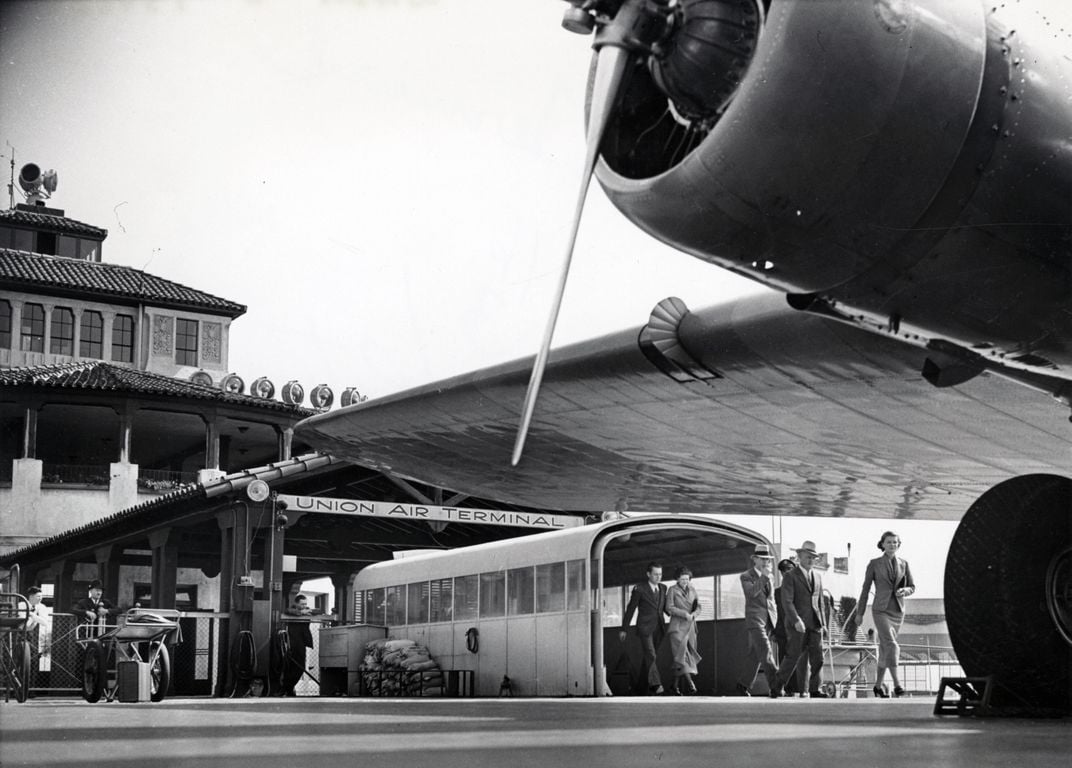 black and white photo of passengers exiting an old airport terminal