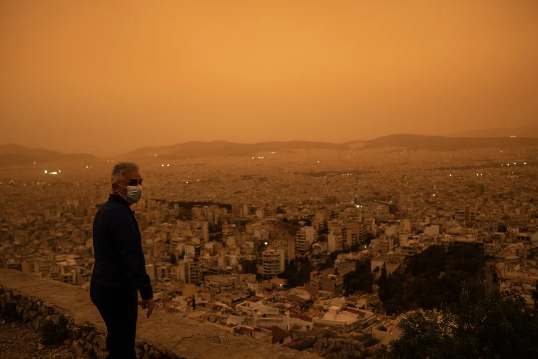 A man wears a face mask, as recommended by health officials, atop Athens' Tourkovounia hill