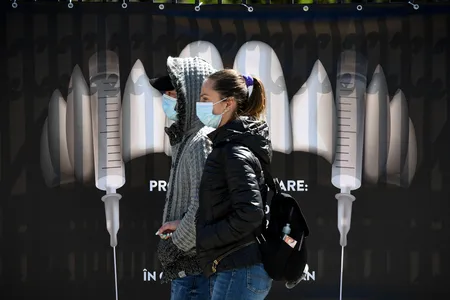 Bran Castle is relying on its connections to the puncture-happy vampire Dracula to entice people to get vaccinated. Here, masked visitors stand in front of a sign depicting syringes as vampire fangs.