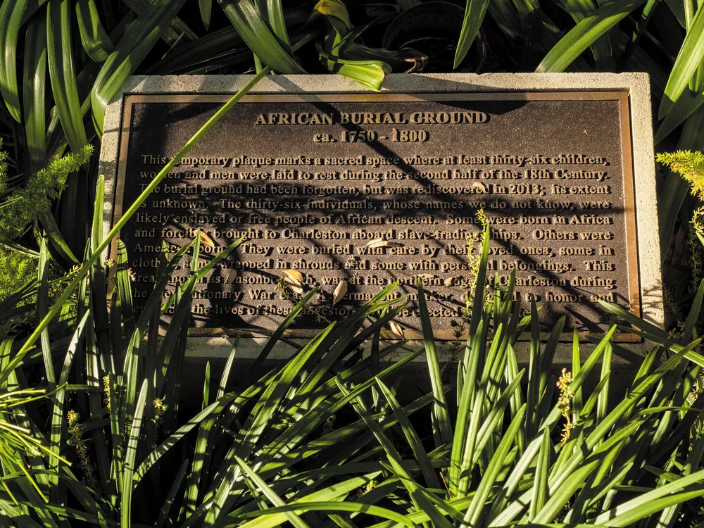 a plaque surrounded by grass honoring the spot where a mass grave was found