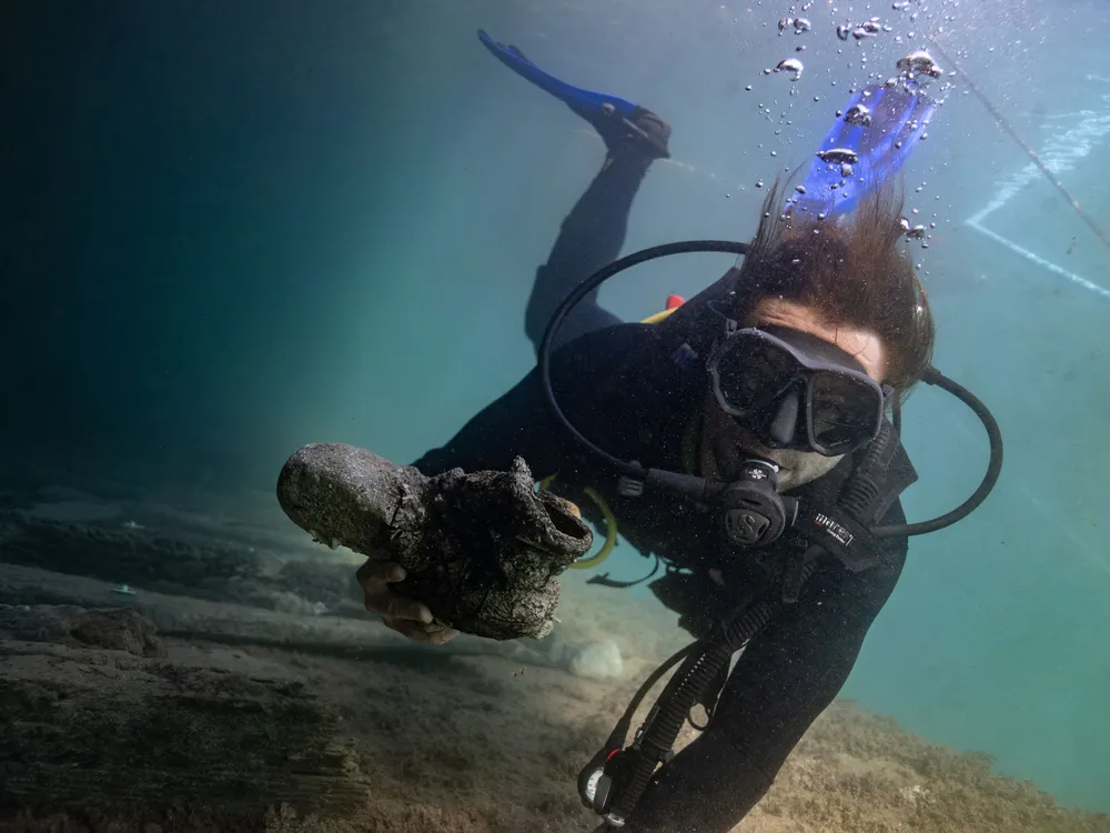 Archaeologist Gino Caspari holds an iron artifact recovered from the shipwrecks.