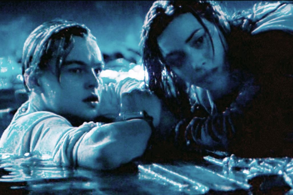 A still from Titanic showing Rose atop the board and Jack clinging to the side