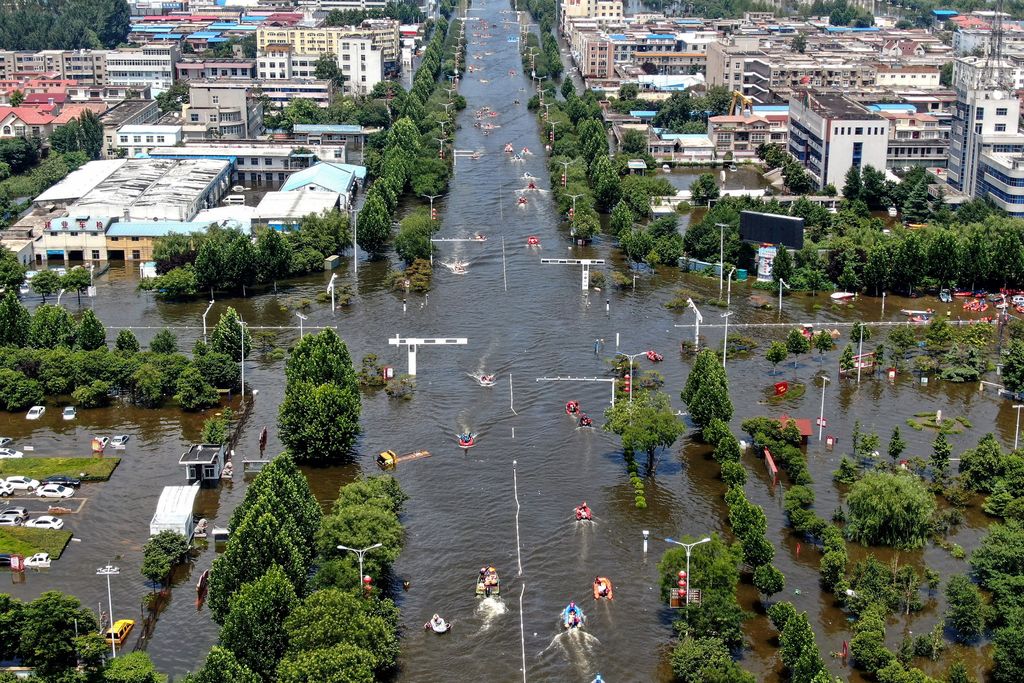 Aerial photo of a flooded intersection with cars, trees and boats after heavy rainfall