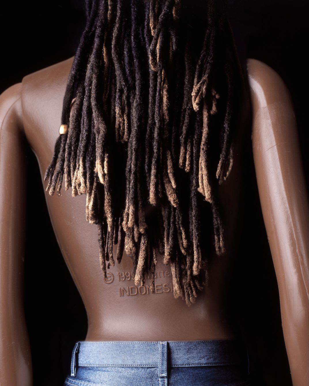 Black toy barbie blended with female real hair in photo illustration
