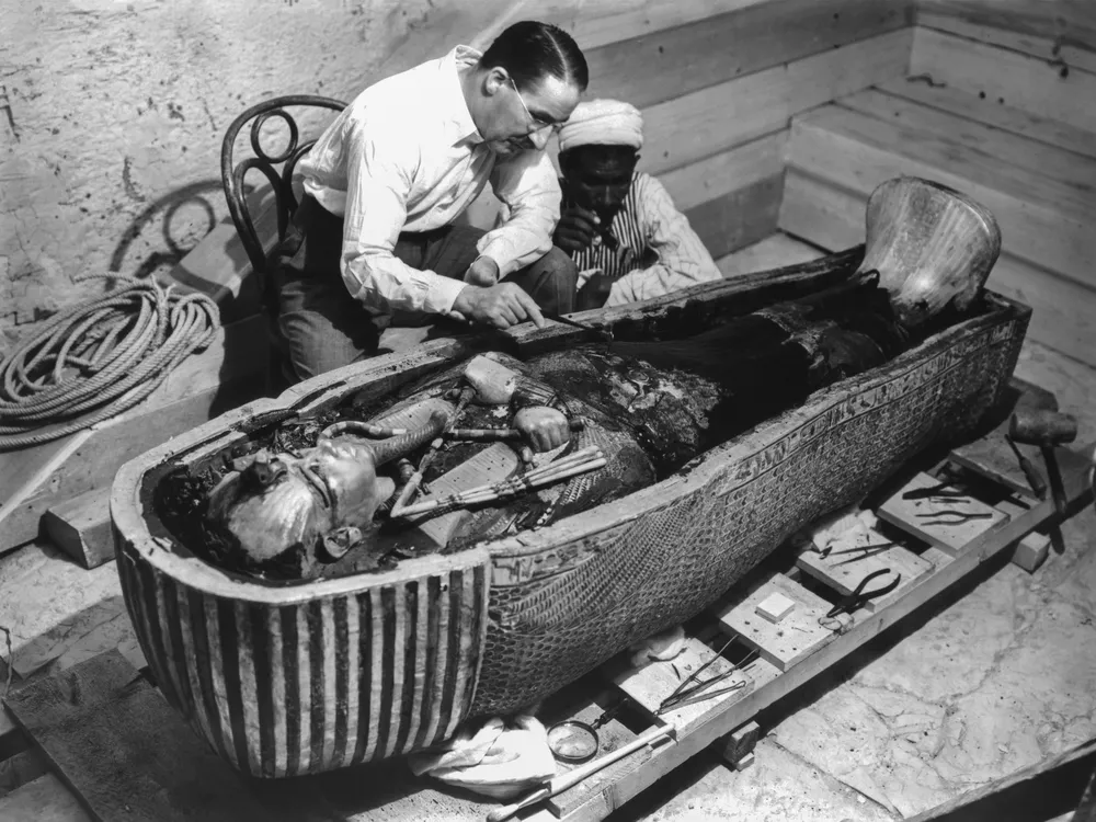Howard Carter and an Egyptian man examining King Tut's sarcophagus