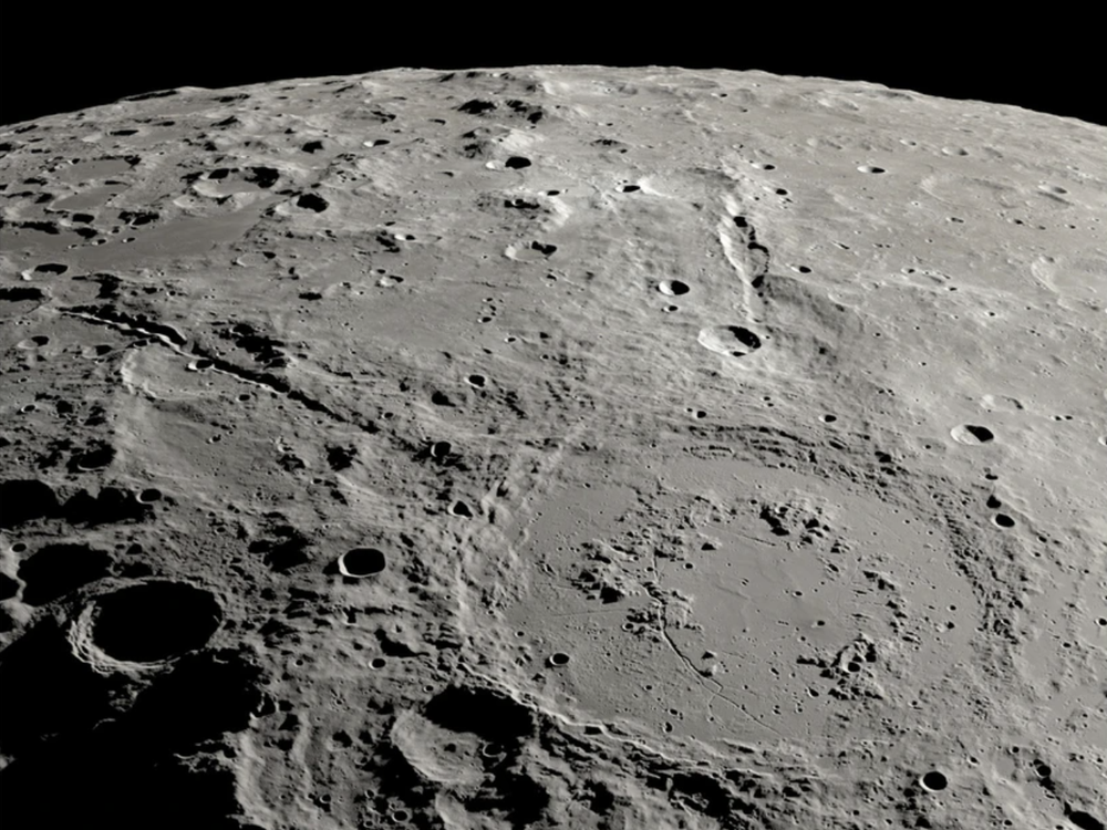 an overhead view of a large crater on the moon with two canyon lines stretching out from it