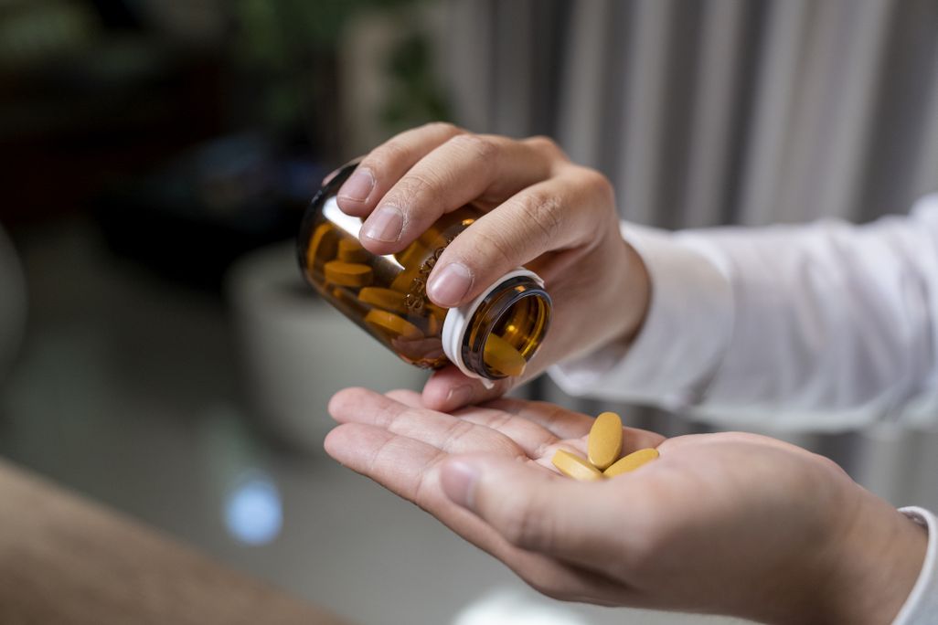 a person dropping pills in the palm of their hand