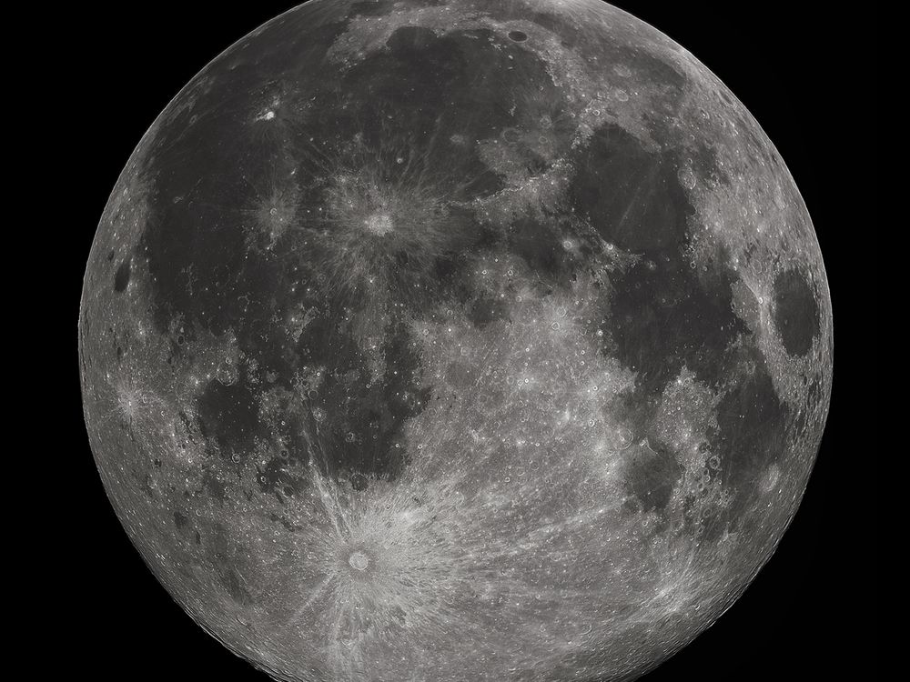 An image of a full moon. The moon looks silver with grey sploches.