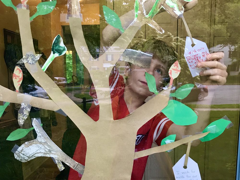 A boy adds a wish for the health of delivery workers during the 2020 pandemic. This  paper wish tree is inspired by artist Yoko Ono’s Wish Tree for Washington, on view at the Hirshhorn Museum’s Sculpture Garden.