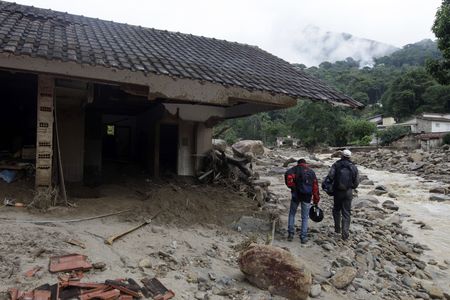 Residents walk near a destroyed house after a landslide in Teresopolis January 15, 2011.
