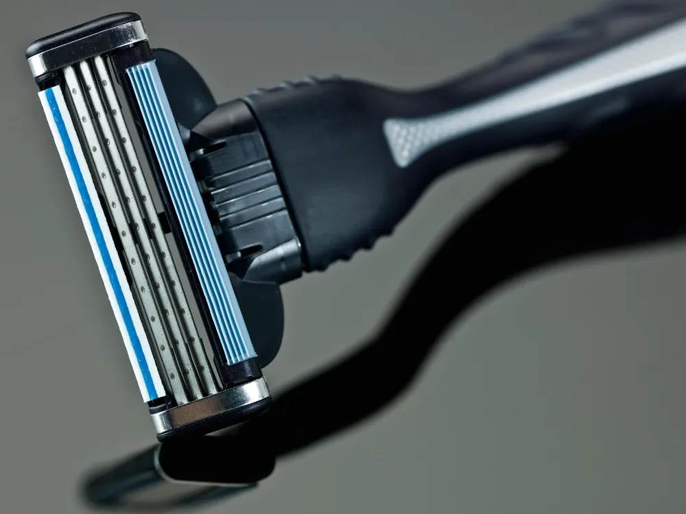 A standard three-blade razor with black and gray handle