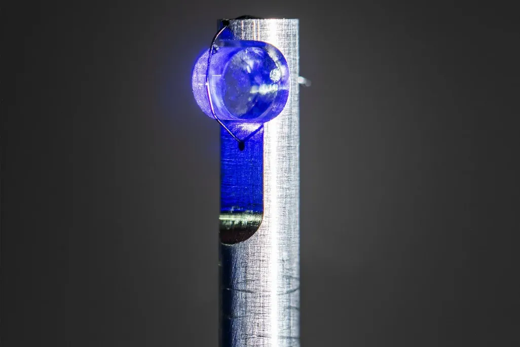 metal pole with a cylindrical crystal illuminated in blue light