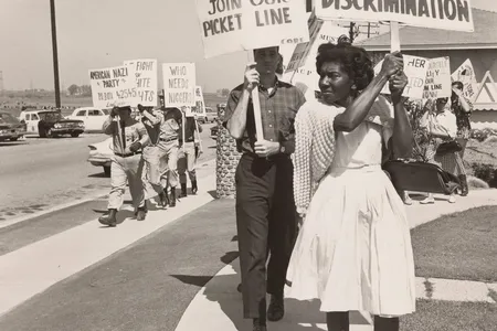 Activists picketing at a demonstration for housing equality while uniformed American Nazi Party members counterprotest in the background with signs displaying anti-integration slogans and racist epithets.