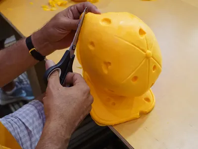 A guest trims the excess foam off a baseball cap.