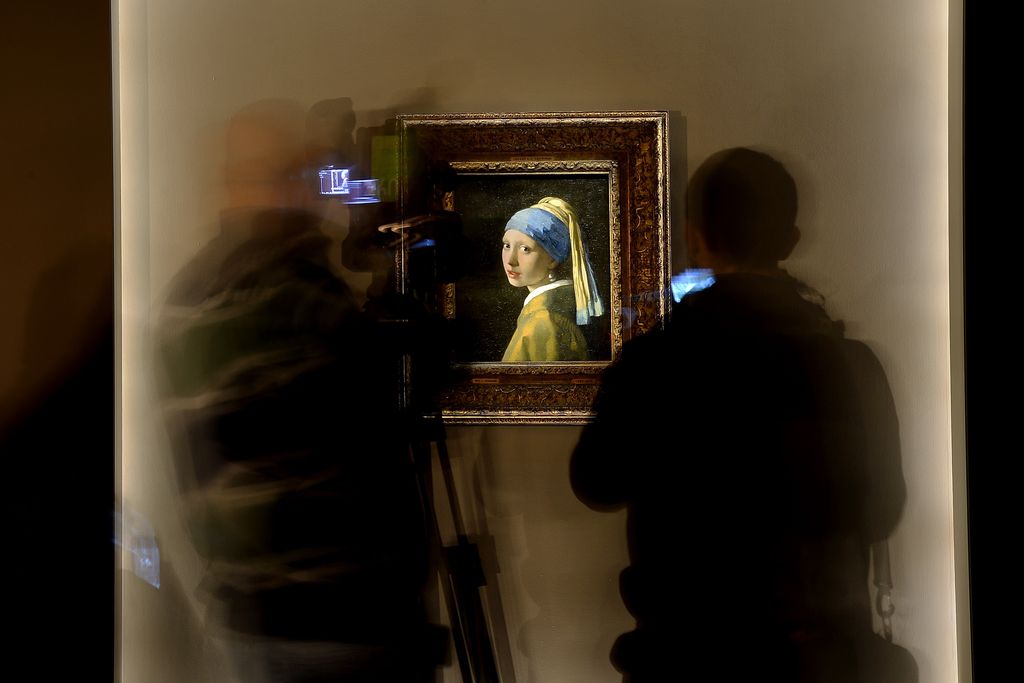 Journalists pass by the painting by Johannes Vermeer entitled Girl with a Pearl Earring