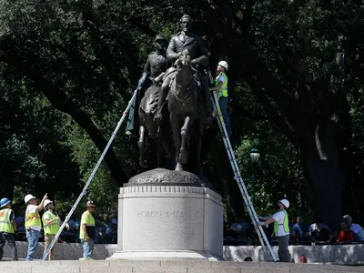 Workers inspect a statue of Robert E. Lee in a public park in Dallas, Wednesday, Sept. 6, 2017.