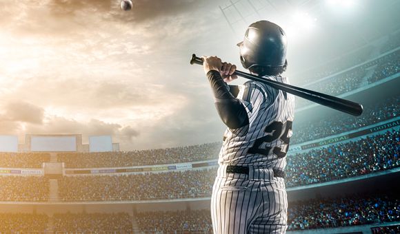 A baseball player hits a ball while at bat in a crowded stadium