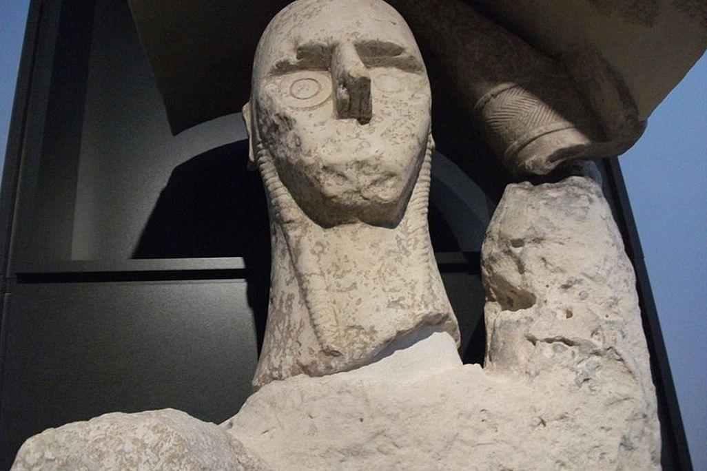 A giant statue of the face and neck of a boxer displayed in a museum.