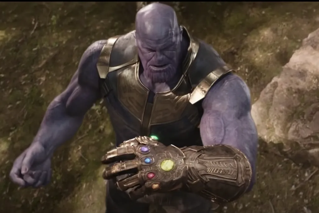 Thanos, a villain in the Marvel universe is a giant, burly purple man wearing gold armor. He wears the Infinity Gauntlet, a large metal glove with six colorful stones embedded—on his left hand.