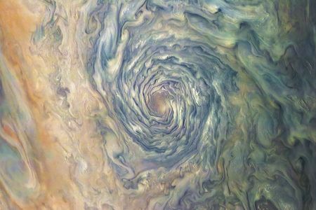 A massive atmospheric vortex on Jupiter is a dizzying swirl of brown, yellow, and green clouds that form a deep tunnel.