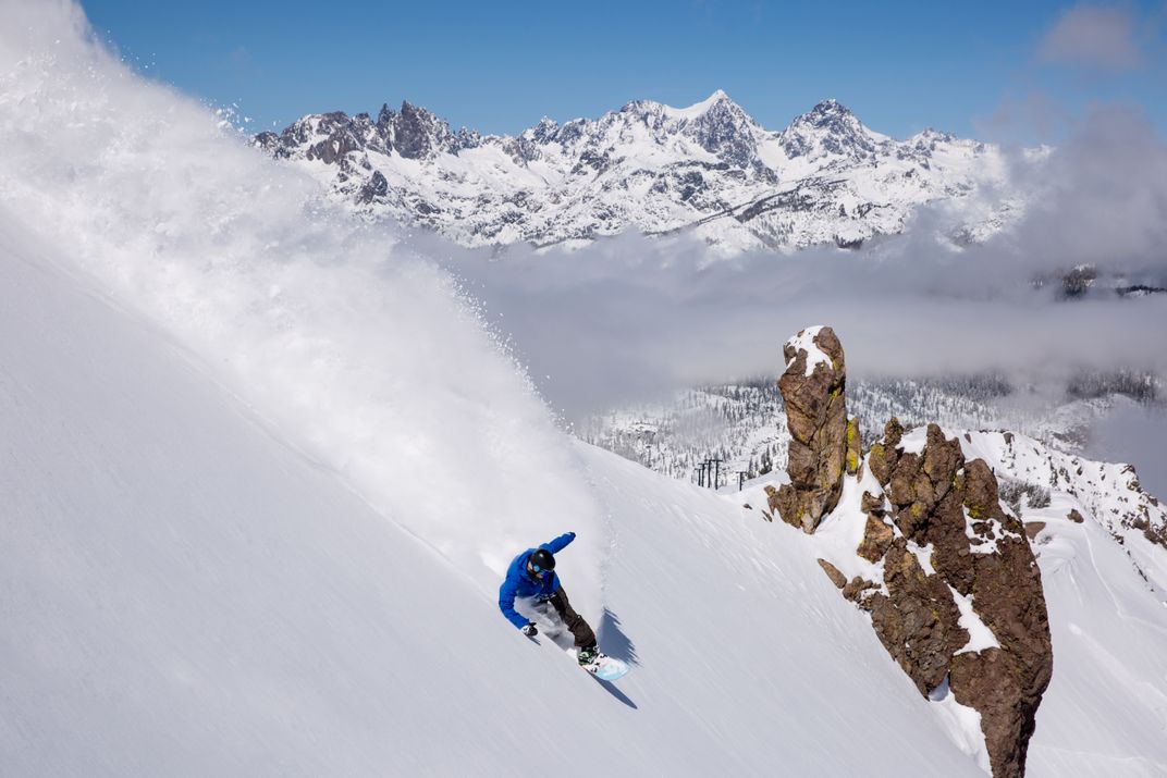 Snowboarder riding down snow-covered mountain