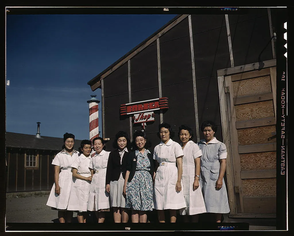 Eight women stand in front of the barber shop at Tule Lake.