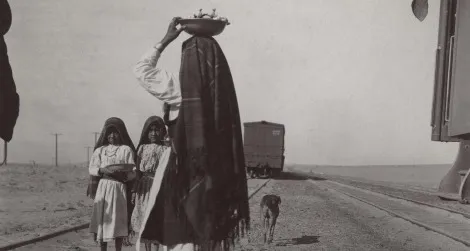 An Isleta woman and her children sell goods alongside a train track, circa late 1880s to early 1900s