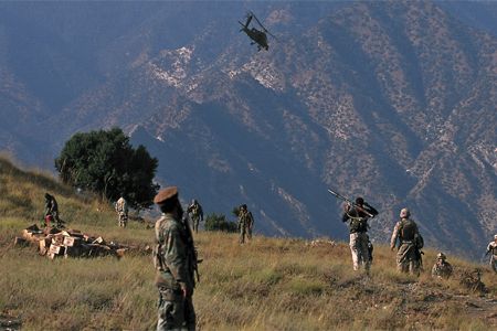 In Afghanistan, Marines and Afghan forces patrol under cover of an AH-64 Apache.