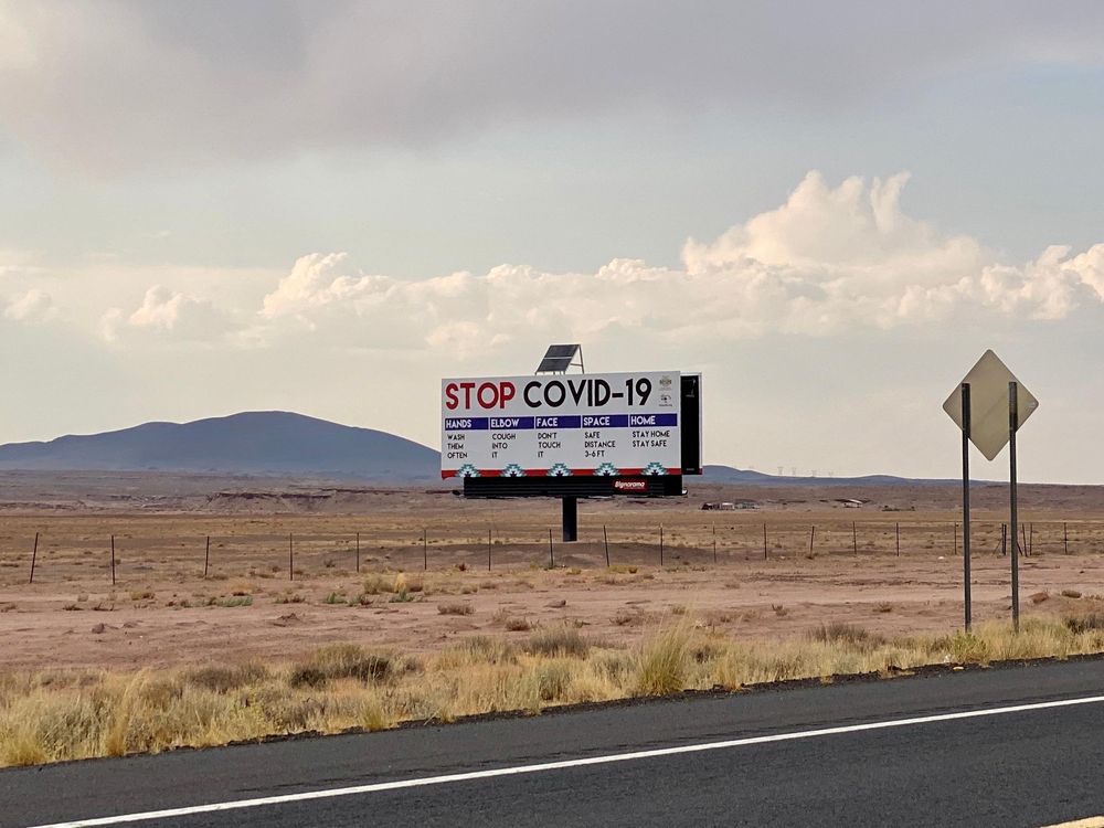 A billboard that reads "STOP COVID-19" stands out in the desert along Route 89 in Arizona